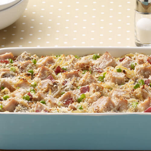 Tetrazzini in a baking dish, covered with cheese, peas, and JENNIE-O® Turkey.