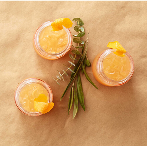 Cups of bourbon and spice sipper garnished with orange.