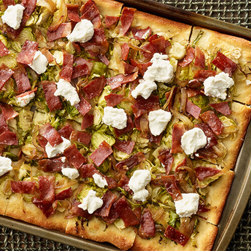 Brussles sprouts turkey bacon flatbread on a wood plank.