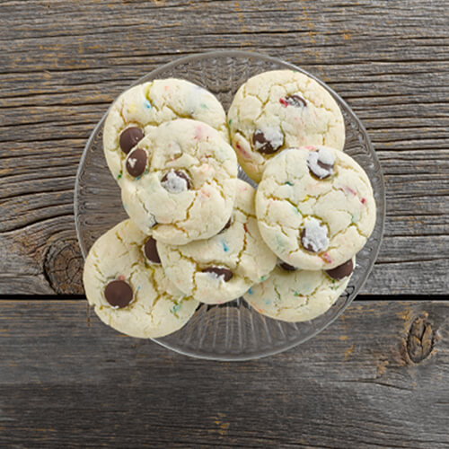 Mixed chocolate chop cookies sitting on a glass dish on a wood table.