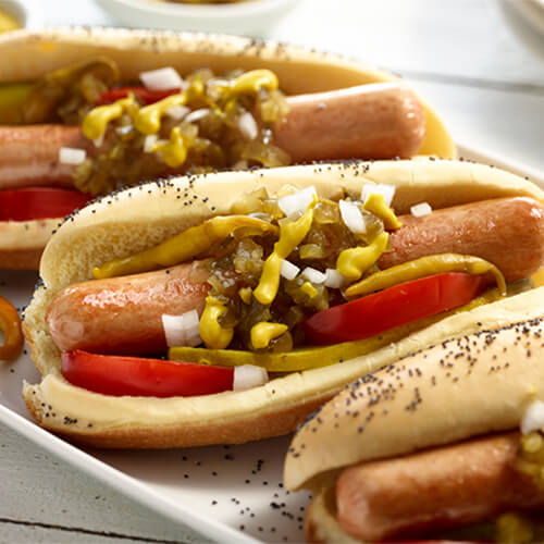 Three turkey dogs topped with tomatoes, mustard, onions, and cheese.