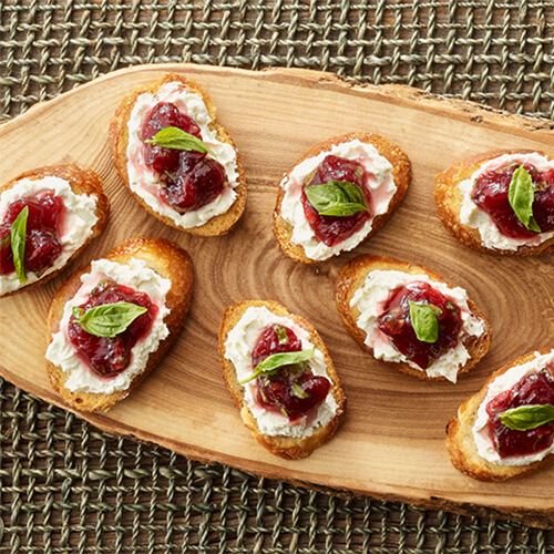 Cranberry goat cheese crostini on a wooden plank.