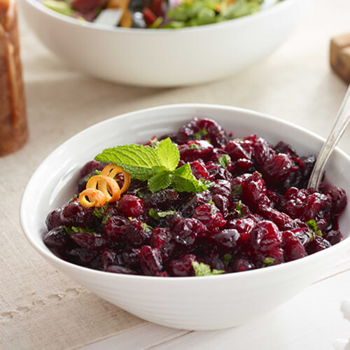 Cranberry orange relish garnished with an orange rind in a white bowl.