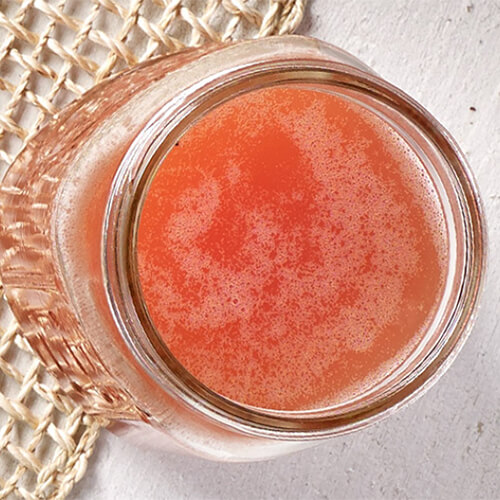 A fresh, bubbly cocktail made with cranberry juice cocktail, orange juice and champagne, served in a mason jar on a wired table mat.