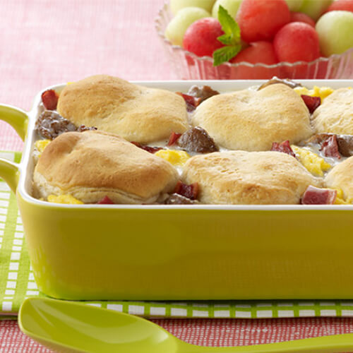 Tasty creamy turkey breakfast casserole topped with biscuits in a green baking pan.