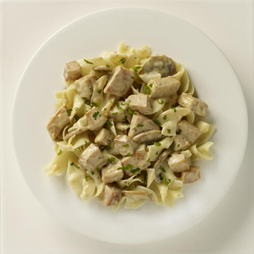 A creamy stroganoff made from mushrooms, roasted turkey breast, sauteed onion and garlic, served over noodles, garnished with parsley.