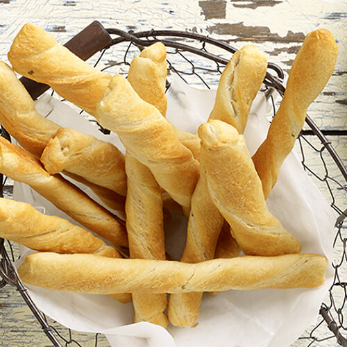 Delicious crescent roll twists with a chive cream cheese, served in a wired bowl on a wooden table.