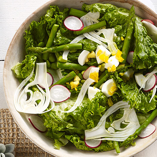 Asparagus and edamame salad in a white bowl.