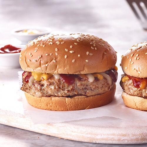 Two turkey cheeseburgers, dripping with ketchup and mustard.