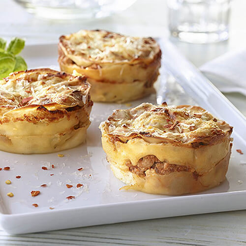 3 magnificent, flaky "cupcakes" made with fresh basil, melted mozzarella and ground turkey served in a white tray and on a white table.