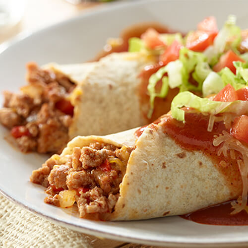 Two enchiladas in flour tortillas filled with ground turkey meat, onions, and topped with enchilada sauce, tomatoes, and shredded lettuce.