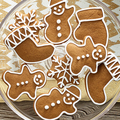 Fun holiday-themed cookies decorated with frosting, served on a glass tray atop a golden tablecloth.