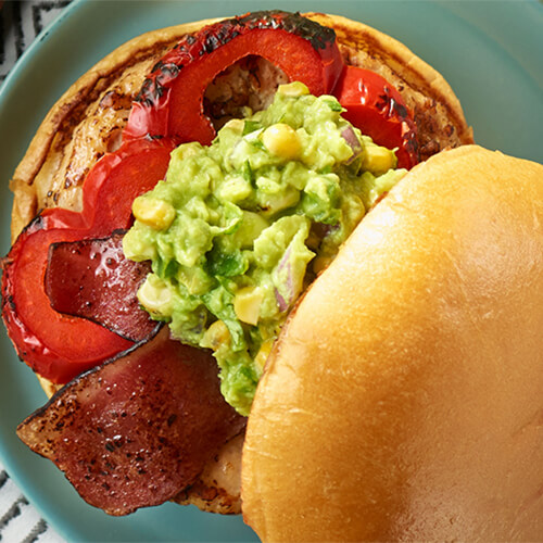 Grilled corn guacamole turkey burger shown open-face on a blue plate.