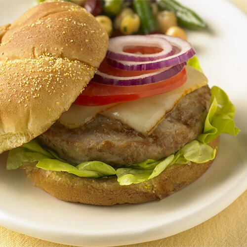 Grilled turkey burger supreme with melted cheese on a white plate.