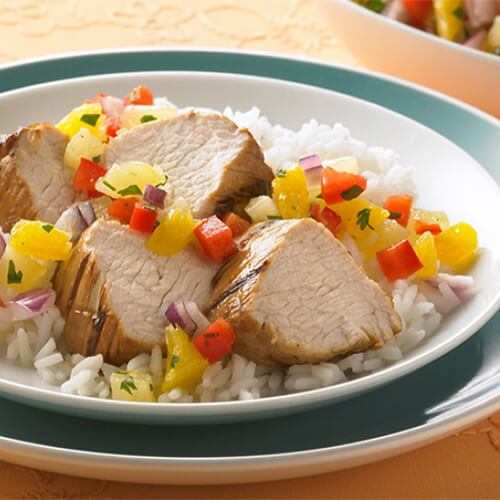 Grilled tirkey with pinapple citrus relish and rice in a white and blue bowl.