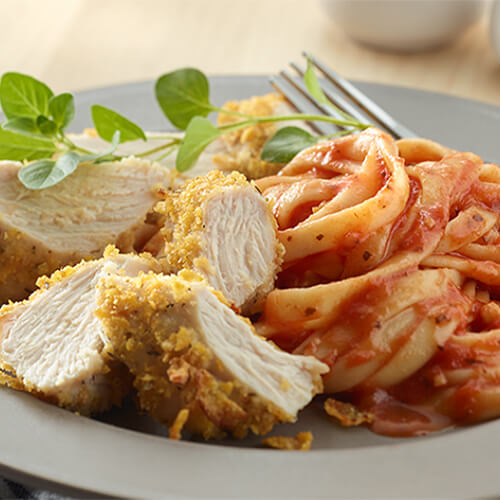 Turkey made with a savory parmesan cheese breading, served with a pasta made with marinara, on a grey shallow plate.