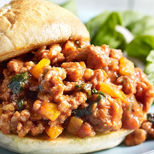 Juicy turkey sausage sloppy joes made with bell pepper and garlic served with a side salad on a blue plate.