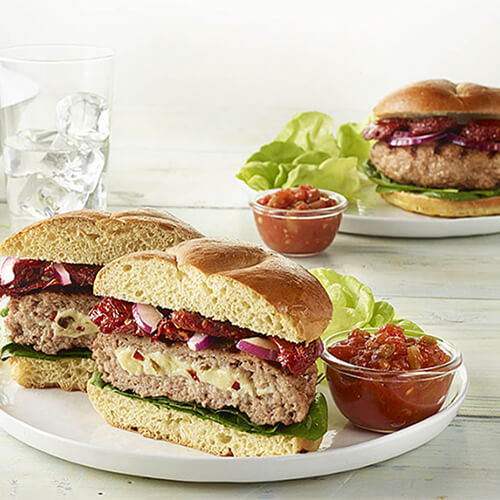 Jalapeno jack savory stuffed turkey burgers with a side of sauce on a white plate.