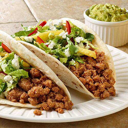 Miami street style turkey tacos with guacamole on a white plate.