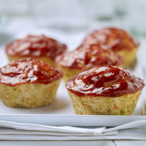 Miniature sized veggie-stuffed turkey meatloaves, spiced and topped with a smoky chipotle sauce, served on a white tray.