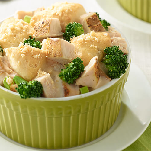 Flaky biscuits, broccoli florets, green onions and slow-cooked turkey filled with alfredo sauce in a green ramekin.