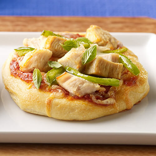 2 mini pizzas topped with, lean turkey, green peppers on a flaky biscuit crust, on a white platter.