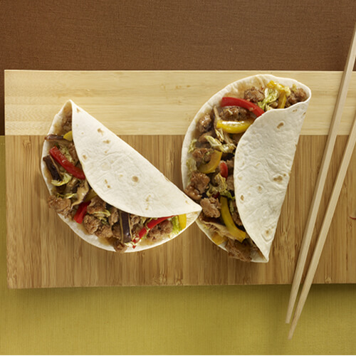 Crunchy veggies, ground turkey, shiitake mushrooms, garlic and ginger root in a flour tattoo on a wooden board.