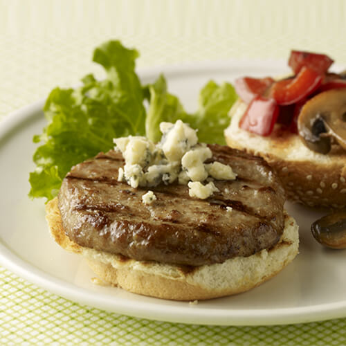 Seared turkey burger on a sesame bun with sautéed mushrooms and red pepper and crumbled blue cheese.