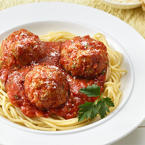 New York turkey meatball and spaghetti garnished with cheese on a white plate.