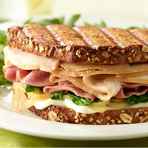 A panini chock full of savory, lean turkey breast, salami, and mozzarella cheese, and topped with basil and caramelized onions.