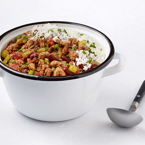 Red beans, lean turkey, and vegetables, served with an great portion of rice all in a white bowl.