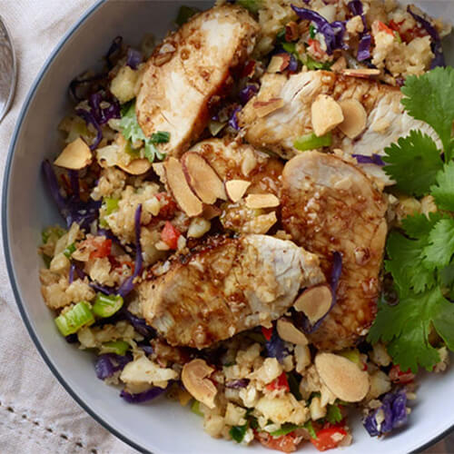 Roasted turkey and cauliflower rice salad garnished with cilantro on a grey bowl.