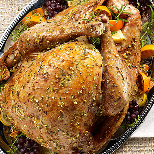 A delicious turkey rubbed with fresh garlic, thyme, rosemary and orange peel, served on a black plate.