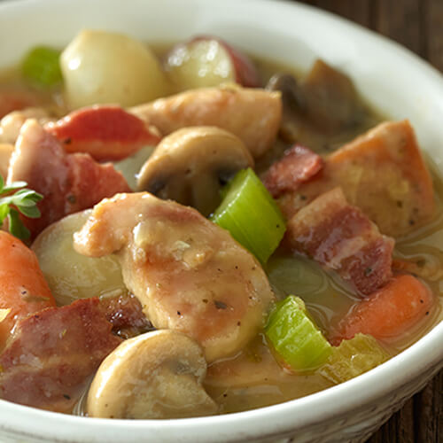 Chunks of turkey, celery, potatoes, in a white bowl of stew.