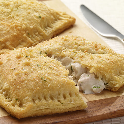 Flaky crust stuffed with JENNIE-O® turkey and cheese on a wooden cutting board.