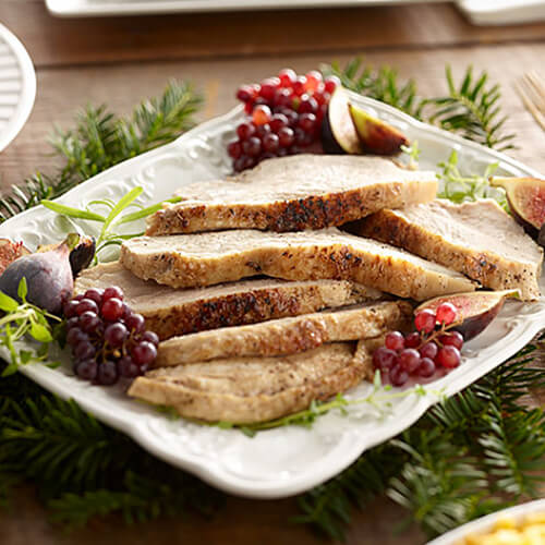 Slow cooker turkey breast garnished with rosemary on a white plate.