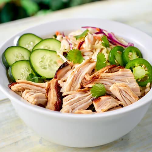 Smoked turkey banh mi bowl garnished with jalapenos in a white bowl.