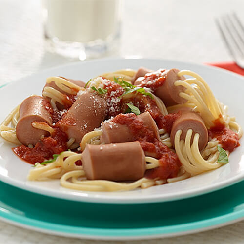 Delicious spaghetti, marinara sauce, with turkey franks, served on a white plate atop a larger blue plate.