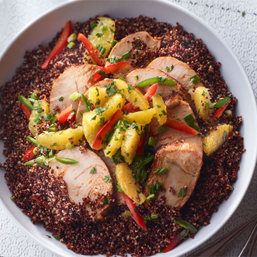 Turkey breast in a bed of red quinoa and topped with vegetables.