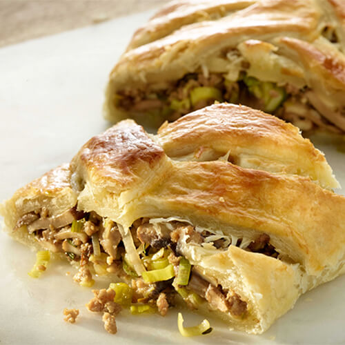 Stuffed turkey braided bread with the filling spilling out on a white plate.