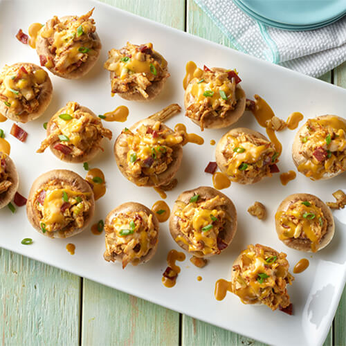 Stuffed turkey mushrooms with the filling falling out on a white tray.