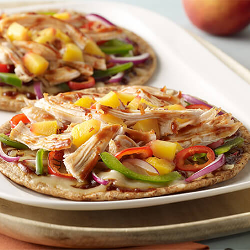 2 sweet flatbread pizzas, topped with barbecue sauce, peppers, and shredded turkey, displayed on a white tray.