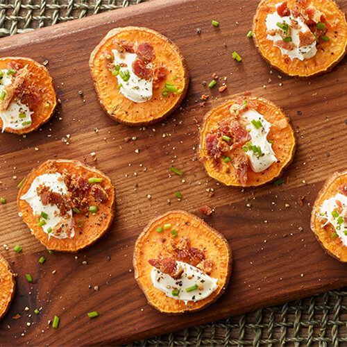 Sweet potato and bacon bites on a wood plank.