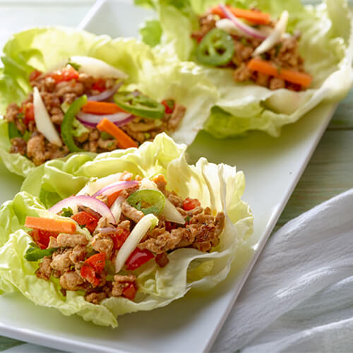 Turkey with lettuce wraps on a white plate.