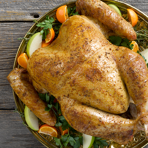 Roasted whole turkey with vegetables on a wood table.