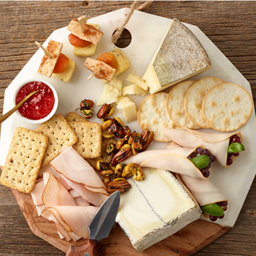 Turkey cracker and cheese plate with sauce on a white plate.