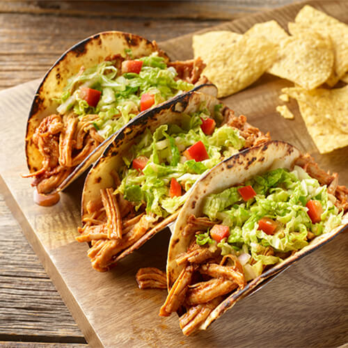 Turkey and Napa cabbage street tacos with nacho on a wood plate.