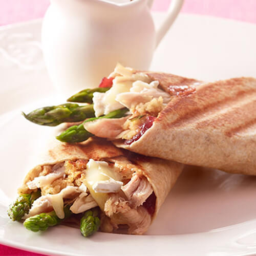 An amazing omelet filled with melted brie, Cajun-style lean turkey breast and fresh asparagus encased in eggs, served in a pan on a white cloth and table.