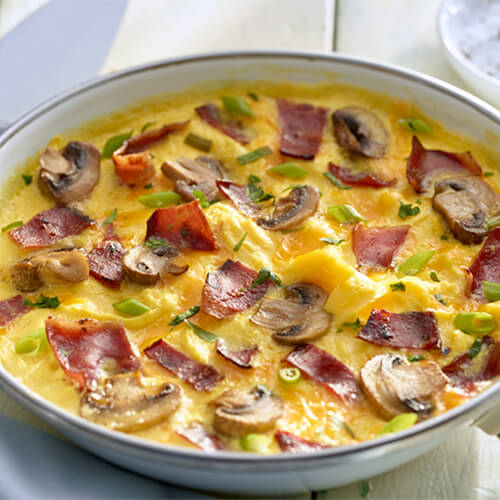 Omelet stuffed with mushrooms, peppers, and JENNIE-O® Turkey Bacon in a white bowl.