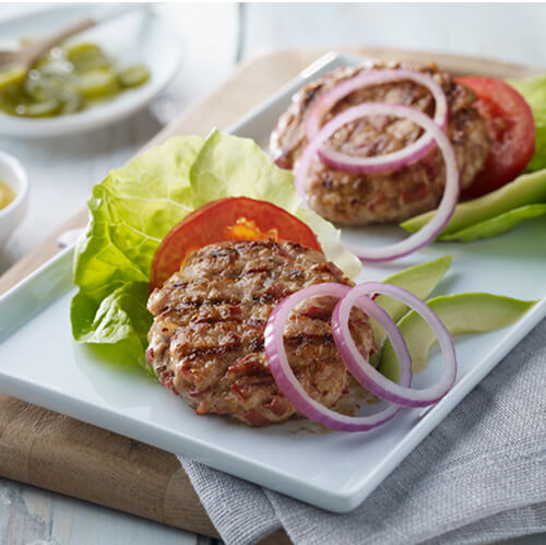 Turkey patties and vegetables on a white square plate.